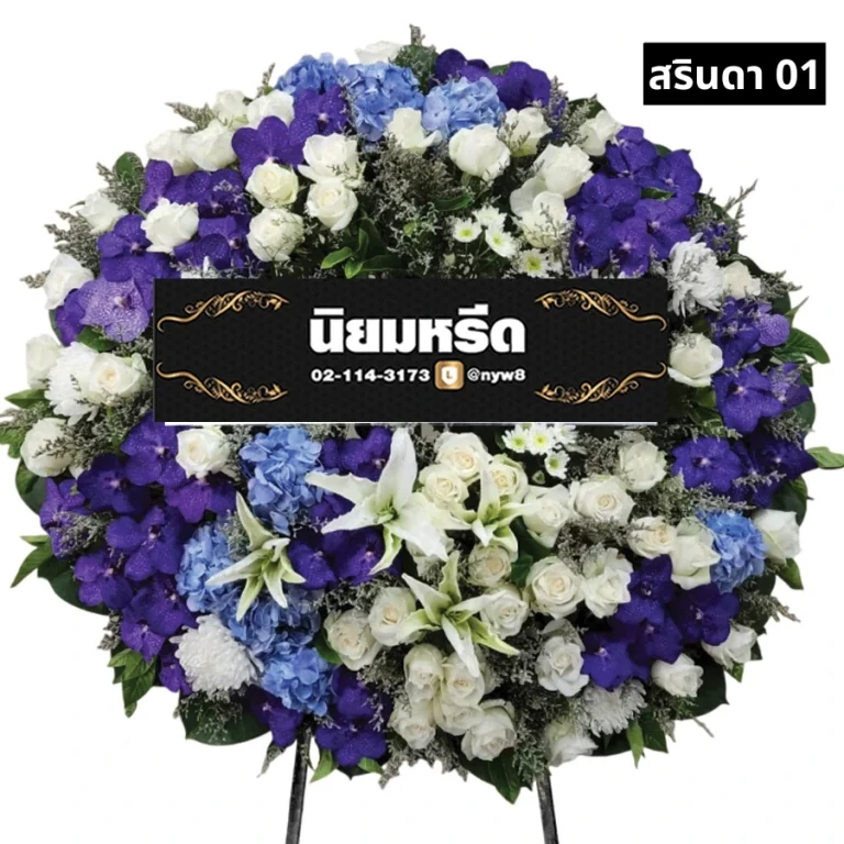 พวงหรีดดอกไม้สด สรินดา01 พวงหรีดดอกไม้สดโทนสีน้ำเงิน ม่วง และขาว ประกอบด้วยกุหลาบขาว ลิลลี่ขาว ไฮเดรนเยียฟ้า และกล้วยไม้ม่วง ตกแต่งอย่างประณีตเพื่อแสดงความเคารพและไว้อาลัย